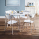 Dining area with a round table and chairs in a room with wooden flooring and blue walls.