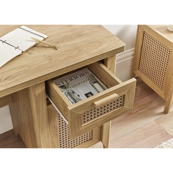 Wooden side table with open drawer containing a magazine, on a wooden floor.