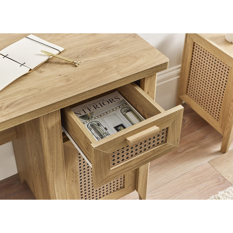 Wooden side table with open drawer containing a magazine, on a wooden floor.