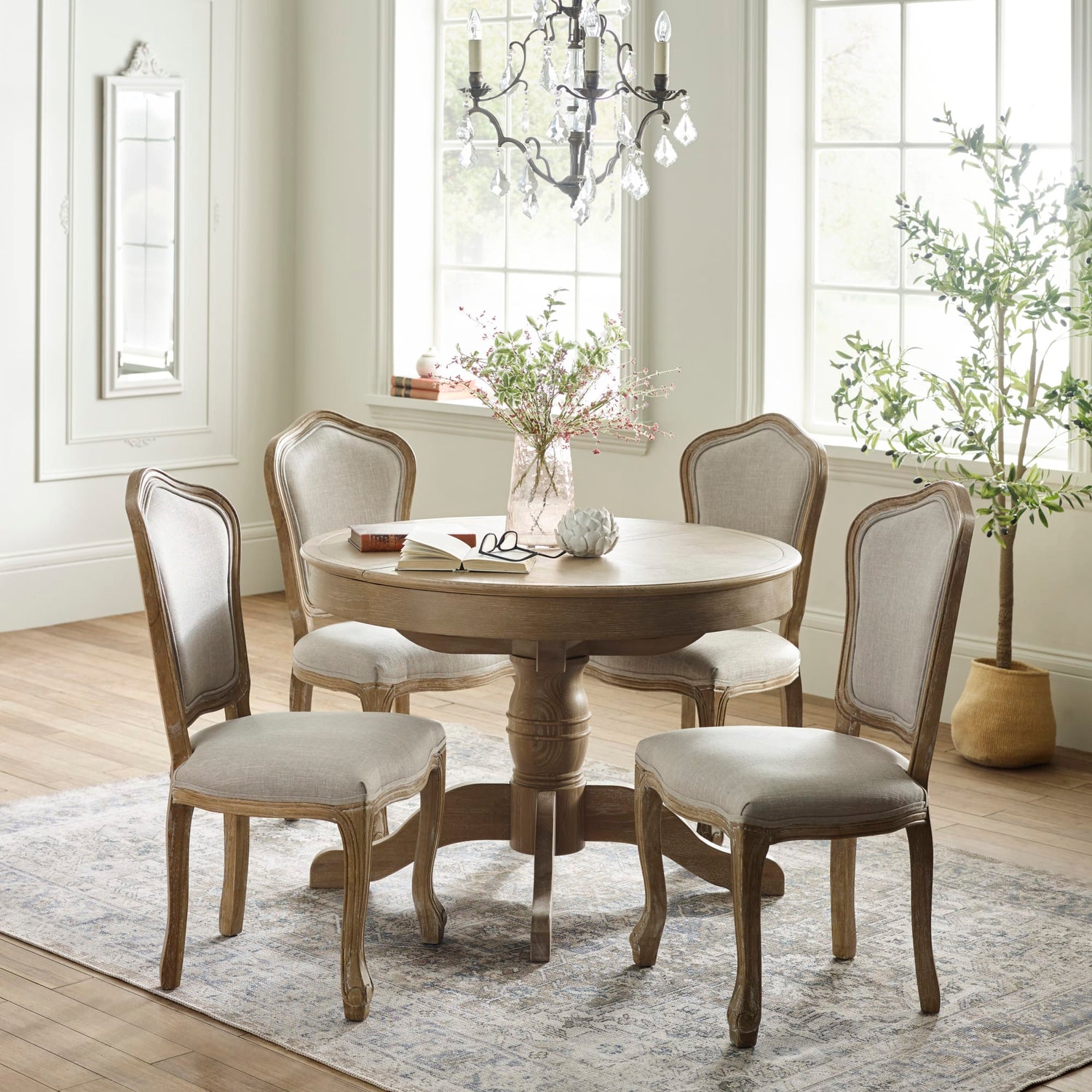Dining room with round wooden table and four chairs in a well-lit room.