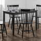 Black dining table with four chairs in a room with white walls and wooden flooring.