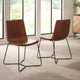 Two brown leather chairs with black metal frames in a room with large windows.