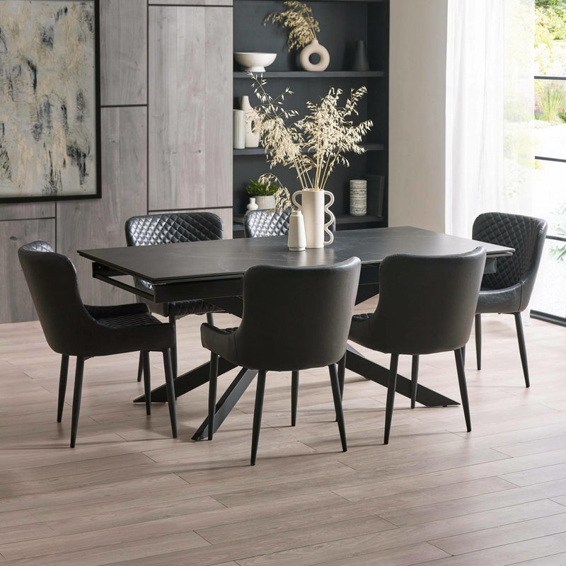 Dining room with a black dining table and chairs on a wooden floor.