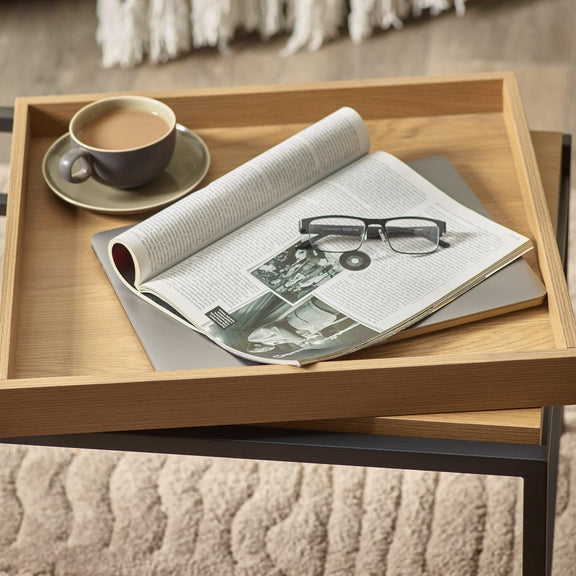 Wooden tray with a newspaper, glasses, and a cup on a textured surface