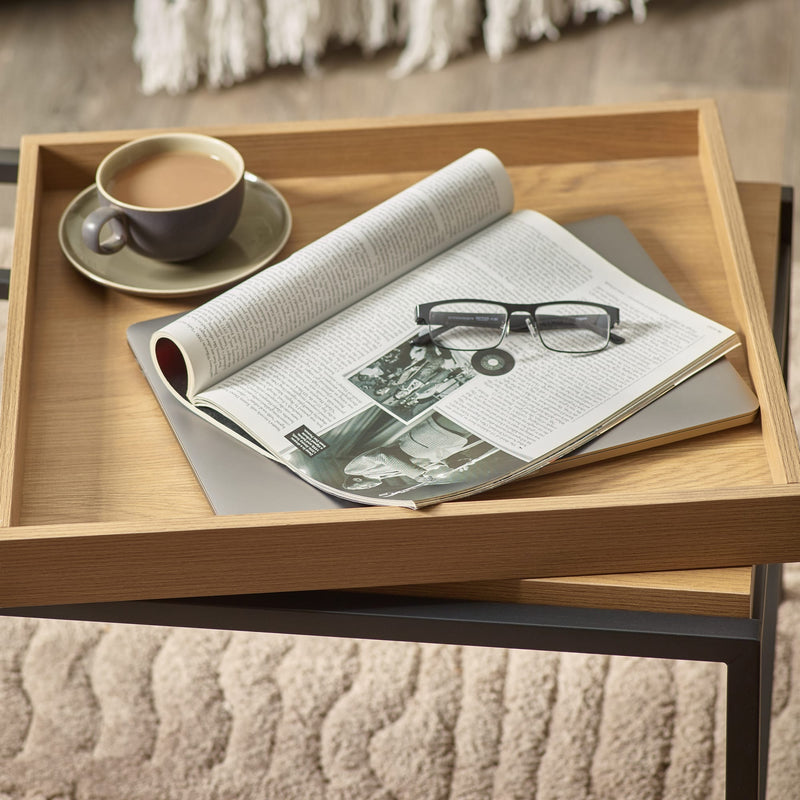 Wooden tray with a newspaper, glasses, and a cup on a textured surface