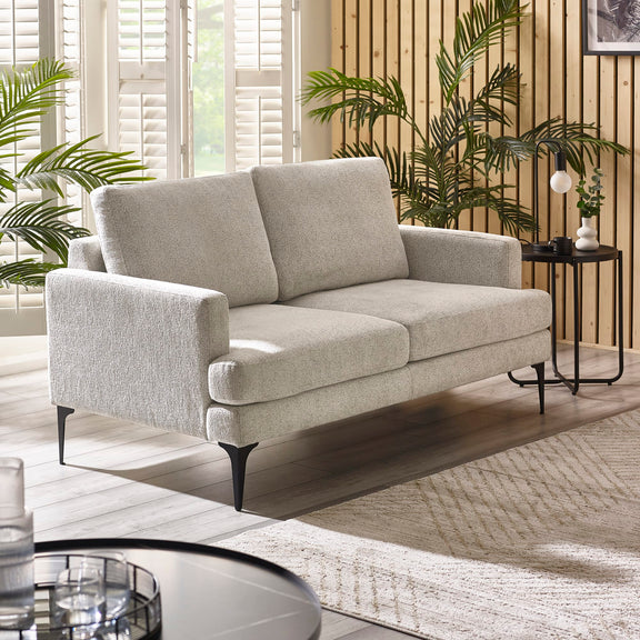 Gray sofa in a living room with plants and a small table.