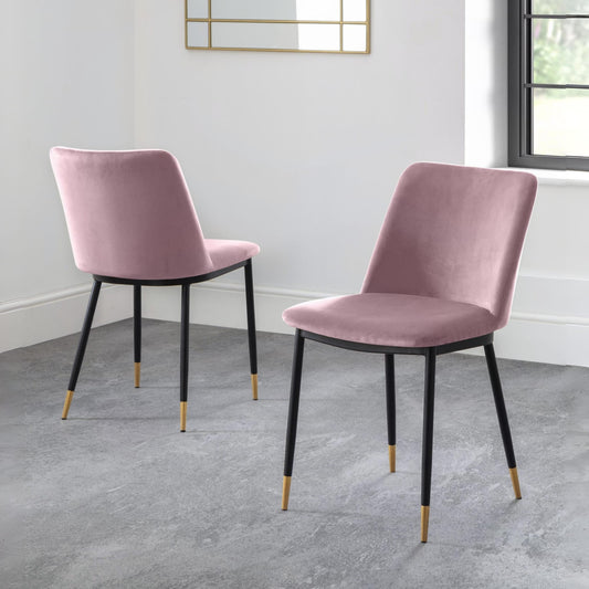 Two pink velvet chairs with black legs on a gray floor.