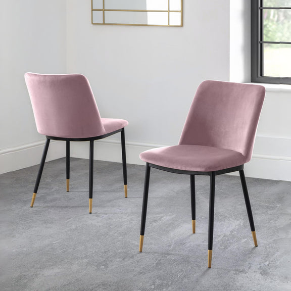 Two pink velvet chairs with black legs on a gray floor.