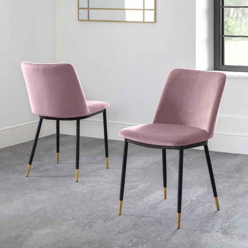 Two pink velvet chairs with black legs on a gray floor.
