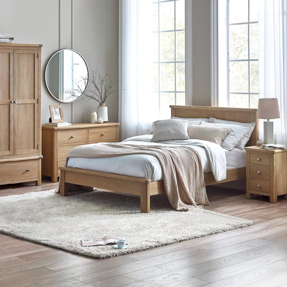 Wooden bedroom furniture set with bed, wardrobe, and side tables in a bright room.