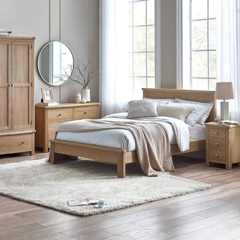 Wooden bedroom furniture set with bed, wardrobe, and side tables in a bright room.