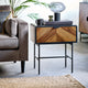 Wooden side table with decorative items next to a gray sofa in a living room setting.