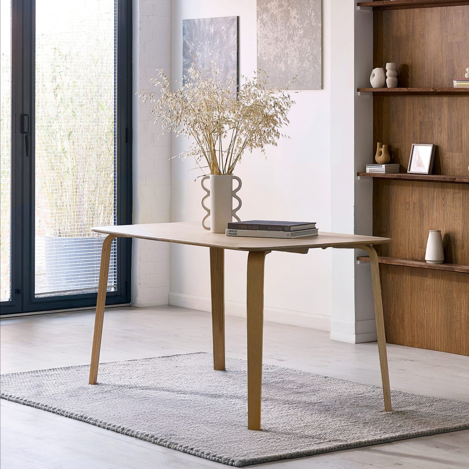 Modern wooden desk in a bright room with a bookshelf and window.