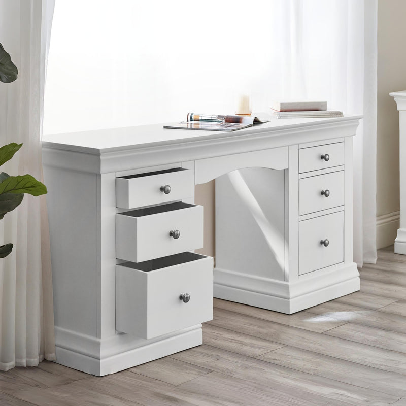 White desk with multiple drawers in a room with curtains and a plant.