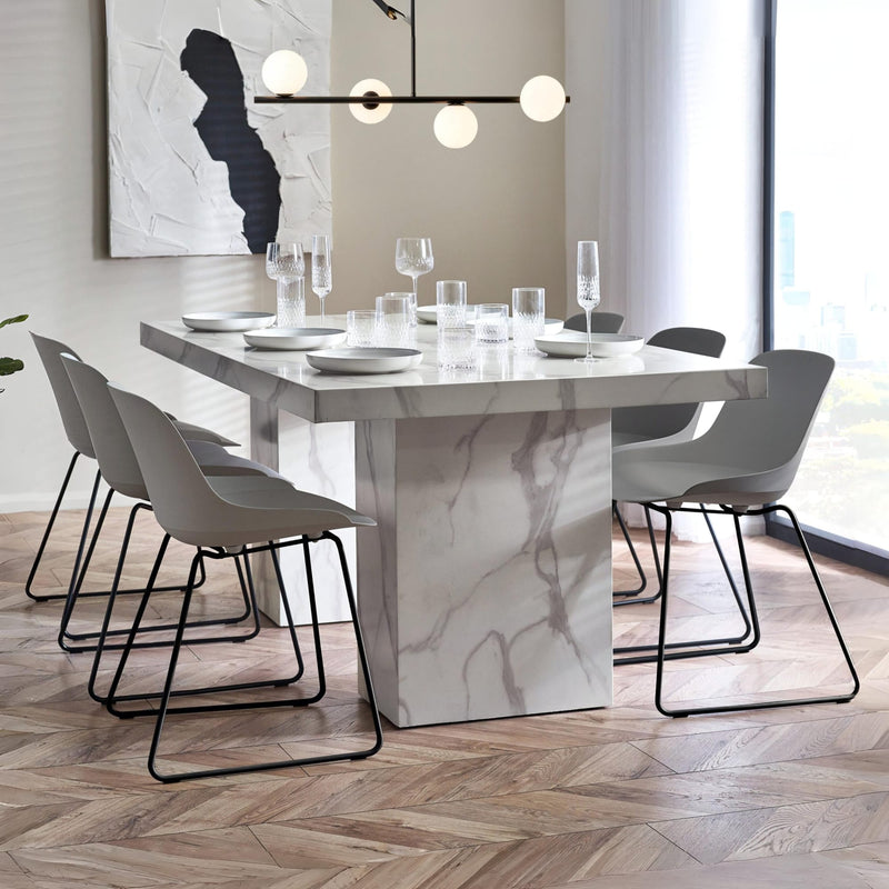 Dining room with marble table and modern chairs in a well-lit room.