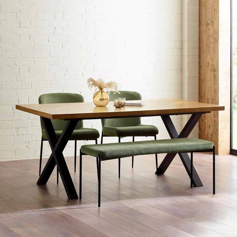 Dining table set with chairs and a bench in a room with wooden flooring and white brick walls.