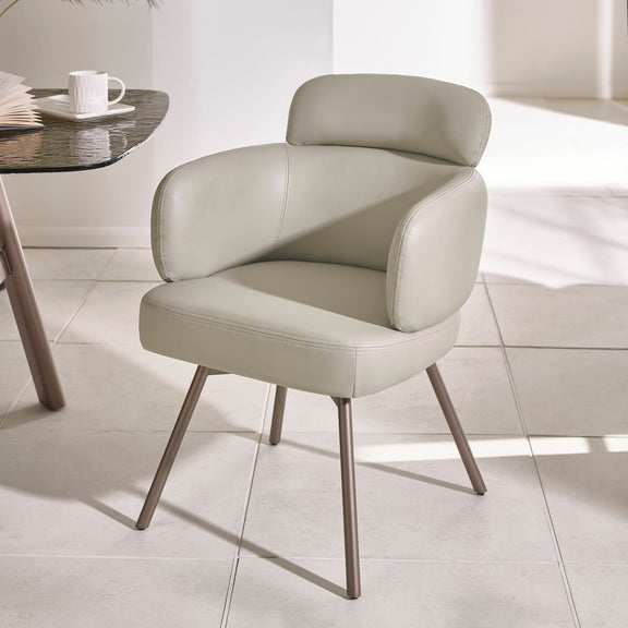Modern beige chair with metal legs on a light tiled floor.