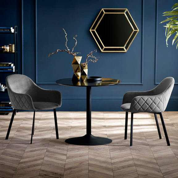 Modern dining setup with a black round table and two gray chairs against a blue wall.