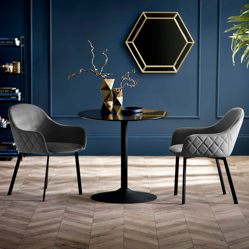 Modern dining setup with a black round table and two gray chairs against a blue wall.