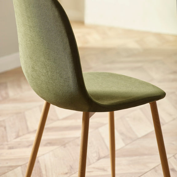 Green chair with wooden legs on a light wooden floor