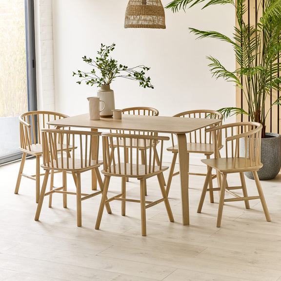 Dining room with wooden table and chairs, plants, and a lamp.