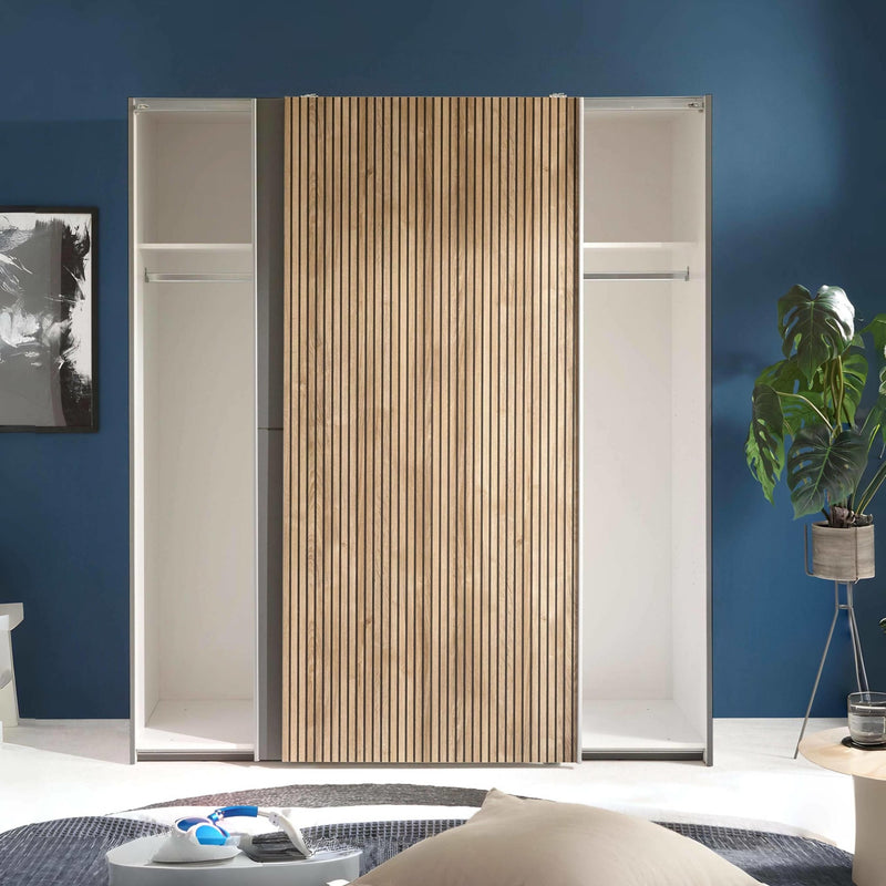 Modern sliding wardrobe with wooden panel in a room with blue walls and a plant.