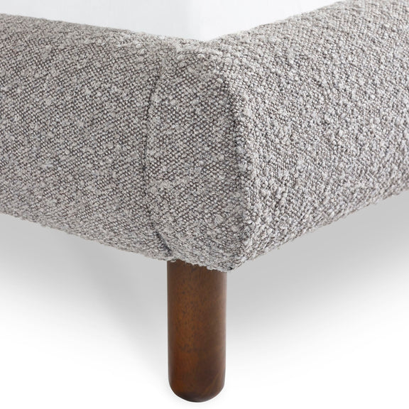 Gray textured bedspread on a bed with wooden bedpost against a white background