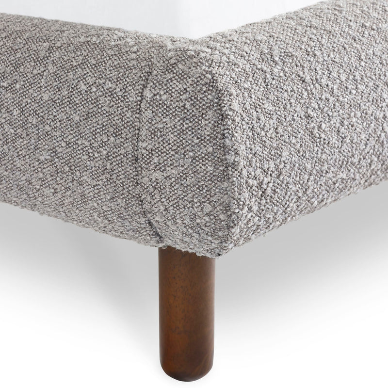 Gray textured bedspread on a bed with wooden bedpost against a white background