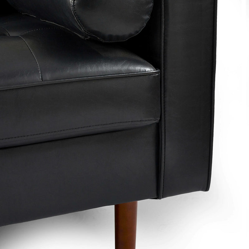 Close-up of a black leather sofa with wooden legs on a white background