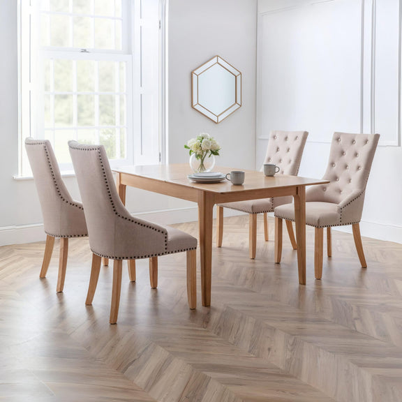Dining room with a wooden table and four upholstered chairs on a wooden floor.