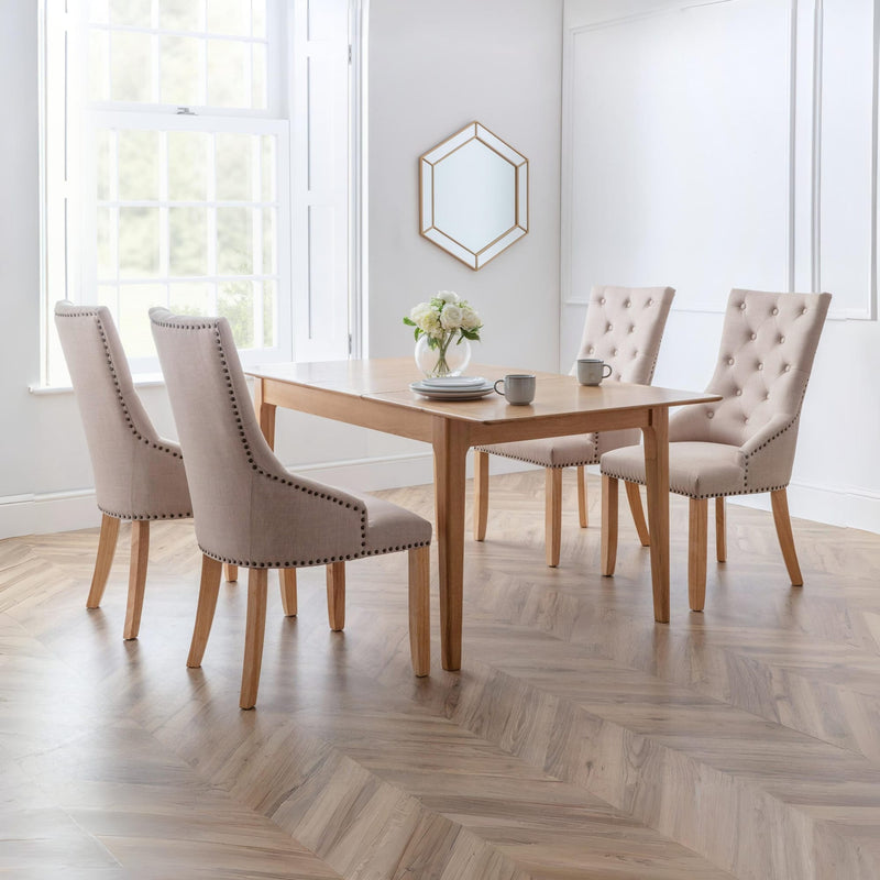 Dining room with a wooden table and four upholstered chairs on a wooden floor.