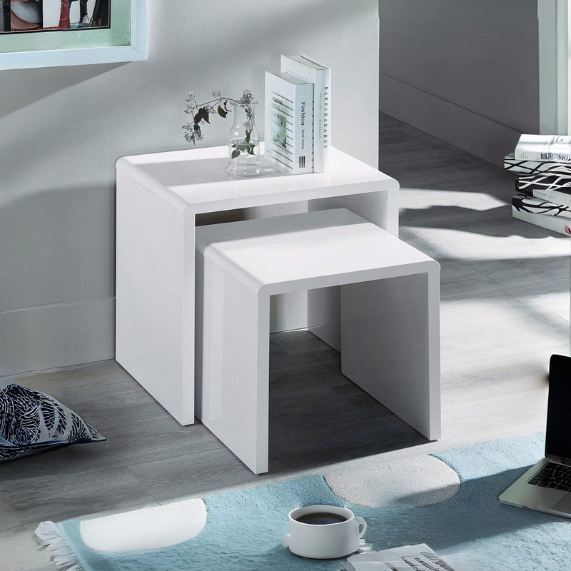 White nesting tables in a room with a rug and coffee cup.