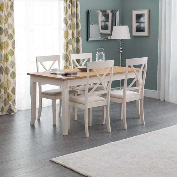 Dining room with a wooden table and white chairs against a green wall.