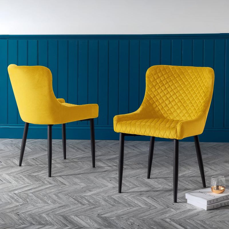 Two yellow chairs with quilted design against a blue wall.