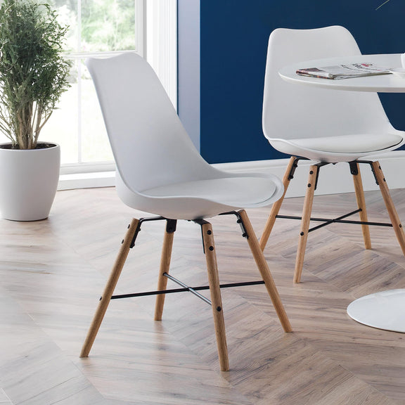 Modern white chairs with wooden legs in a room with a blue wall and a plant.