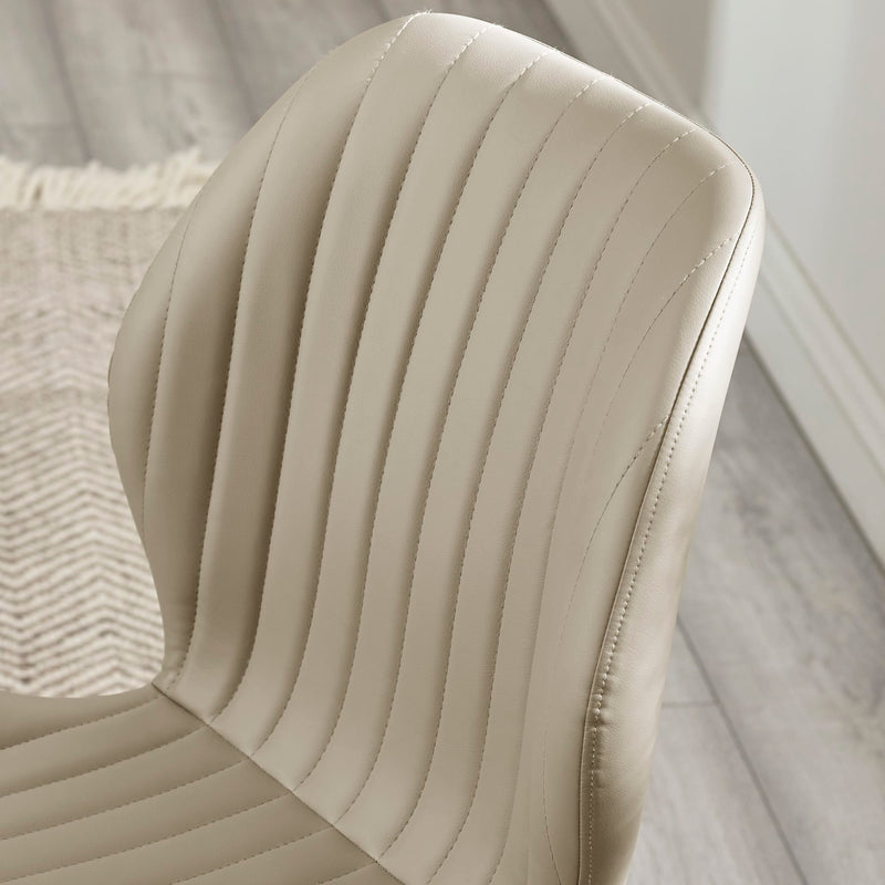 Close-up of a beige leather chair with visible stitching on a neutral background