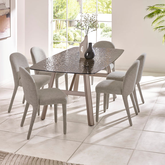 Dining table with six chairs in a bright room with large windows.