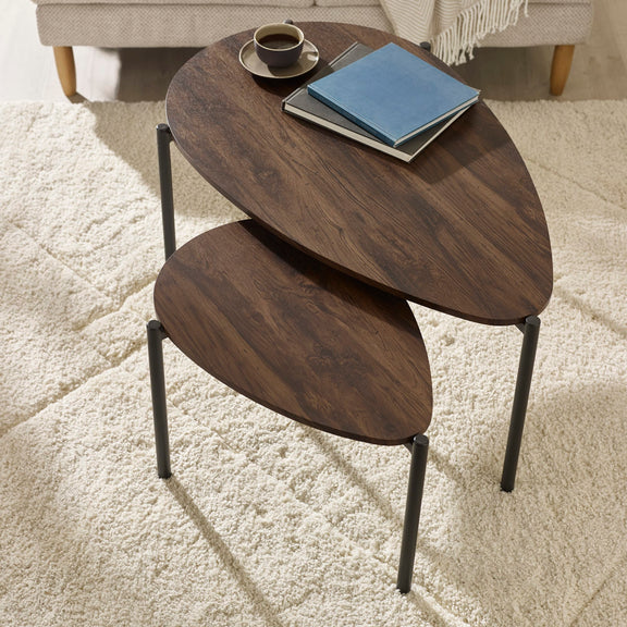 Nest of two wooden side tables with a cup and books on a light carpet