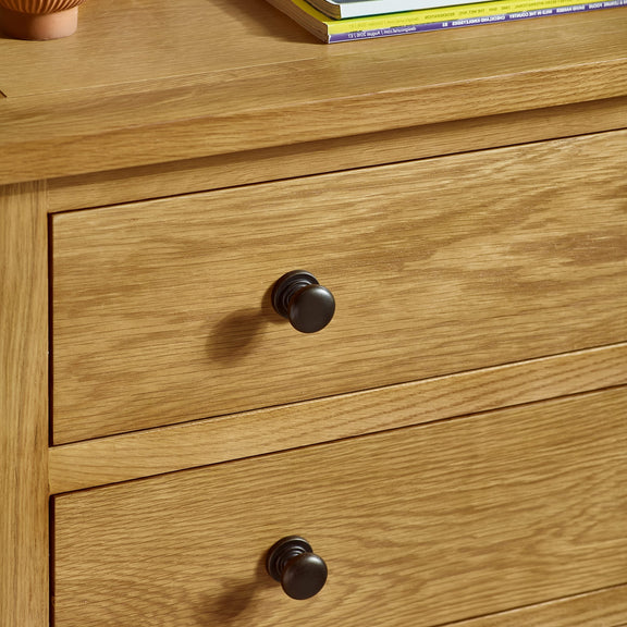 Wooden drawer with black handles on a wooden surface.