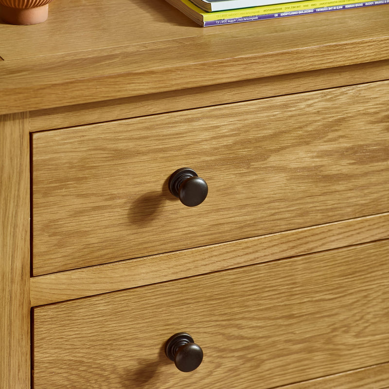 Wooden drawer with black handles on a wooden surface.