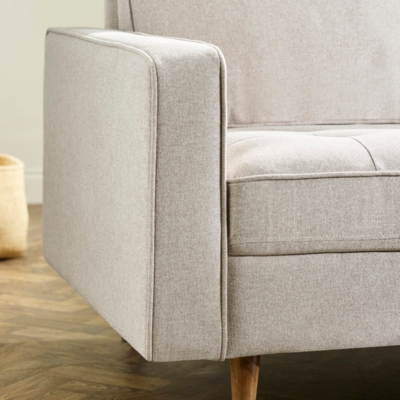 Gray upholstered chair with wooden legs on a wooden floor.