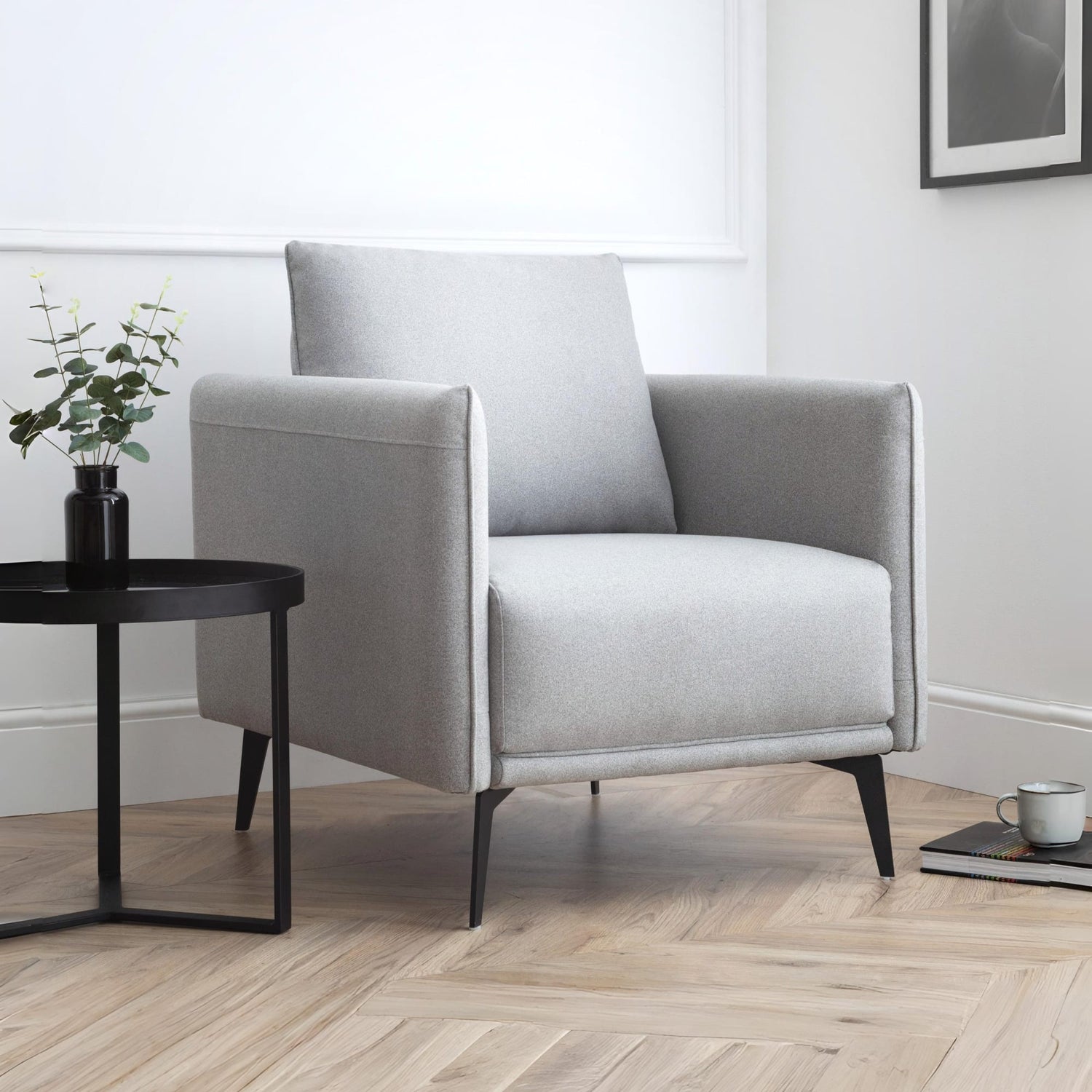 Gray armchair in a modern living room with a side table and plant.