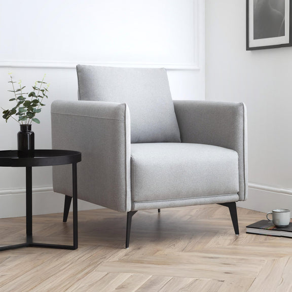 Gray armchair in a modern living room with a side table and plant.