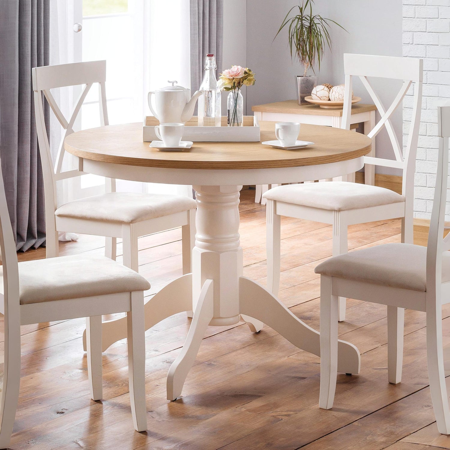 Round wooden dining table with white chairs in a well-lit room.