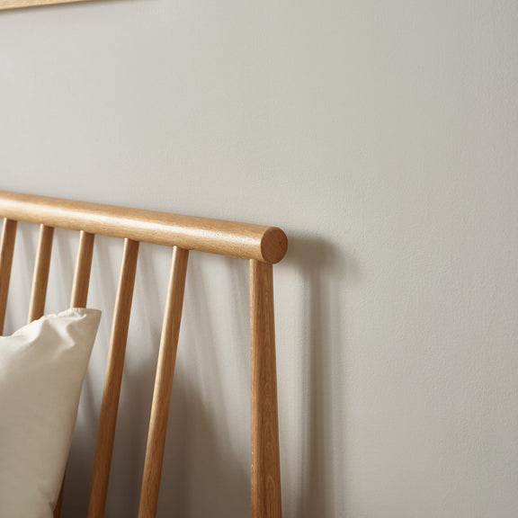 Wooden headboard with a pillow against a plain wall