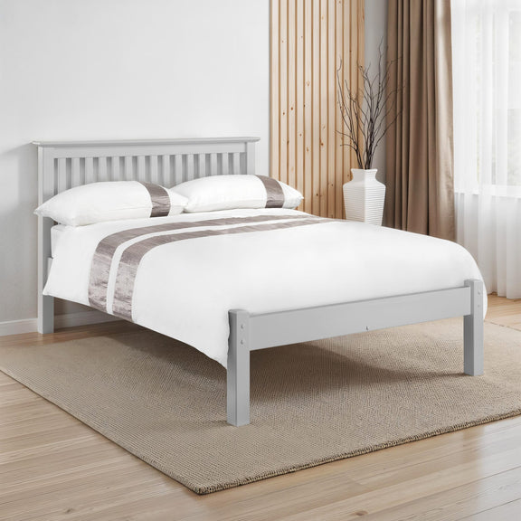 Gray wooden bed frame with white bedding in a room with curtains and a rug.