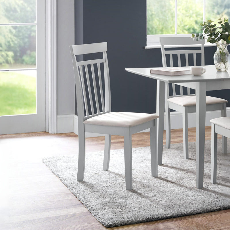 Dining room with a gray table and chairs on a rug, large windows in the background.