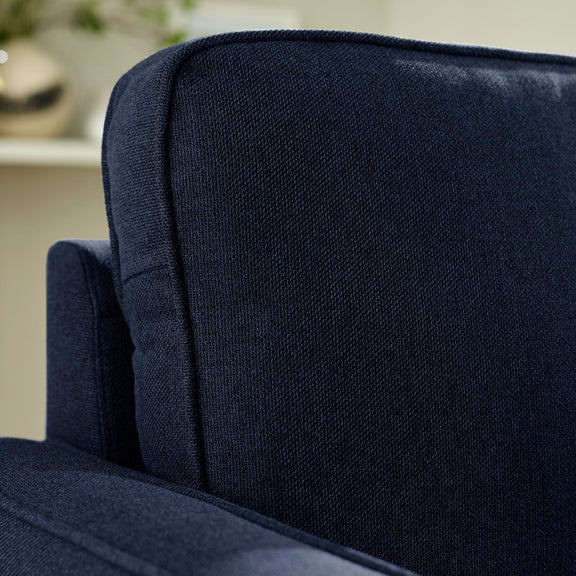 Close-up of a navy blue upholstered chair with a blurred background