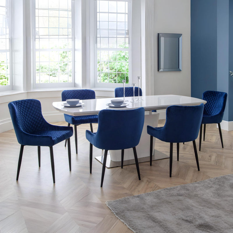 Dining room with a round table and blue chairs in a well-lit room.