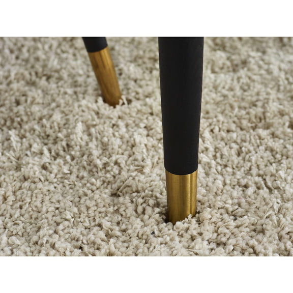 Close-up of a carpet with gold and black furniture leg on a beige carpet